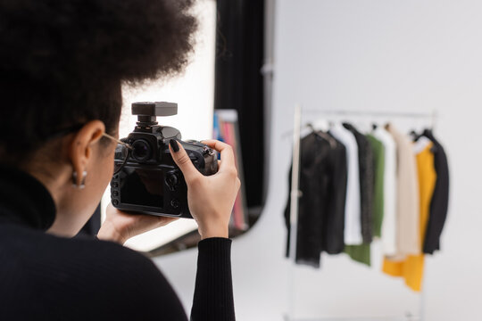 african american content maker photographing blurred collection of clothes in photo studio.