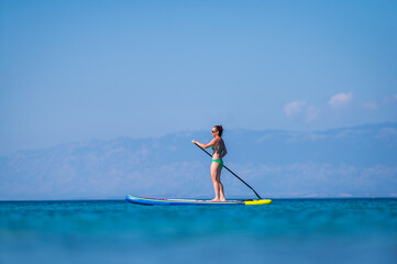 Fototapeta na wymiar Woman riding SUP stand up paddle on vacation.