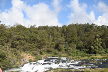 Fototapeta na wymiar River flowing with green hills and blue sky