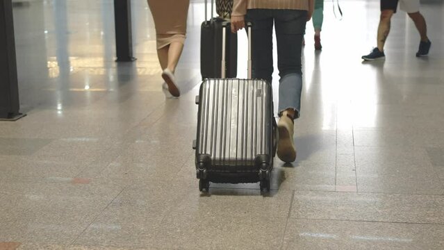 Close up shot of woman dragging wheeled luggage in terminal to check in at airport for travel trip on vacation, Travel concept.