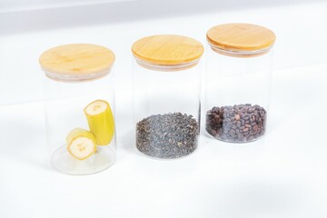 Closeup shot of three jars with bananas and two other spices on a white table