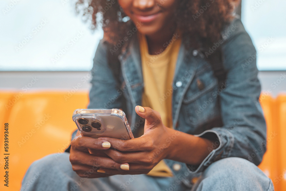 Wall mural closeup - hands of african american woman passenger smile and using smart mobile phone in subway tra