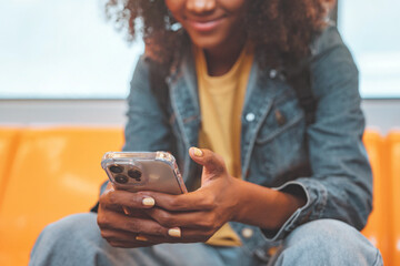 Closeup - Hands of African American woman passenger smile and using smart mobile phone in subway...