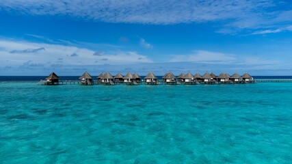 Naklejka na ściany i meble Scenic view of luxurious cabanas in the tranquil ocean against a blue sky in Maldives