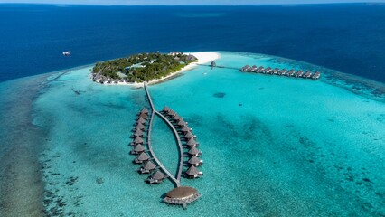 Aerial view of an island with luxurious cabanas in the tranquil blue ocean in Maldives