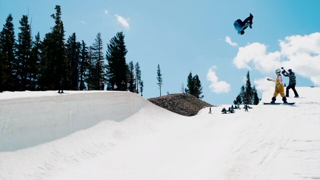 Male Snowboarder training olympics Halfpipe aerial double cork flip slide to the left huge air spring blue sky sunny day at Mammoth California