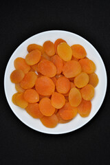 Dried fruits on a white plate. Dried apricot fruit halves without pits close-up.