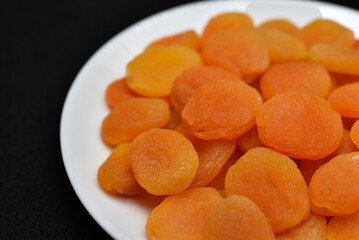 Dried fruits on a white plate. Dried apricot fruit halves without pits close-up.
