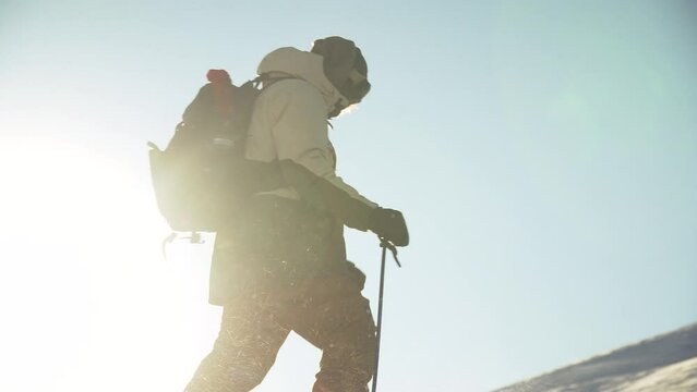 Male backcountry snowboarder splitboard skiing atop mountain pass blue bird sunny fresh snow mountain landscape sunset sun flares at Vail Pass Colorado