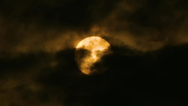 Bright yellow Full Moon with dark clouds moving across slowly