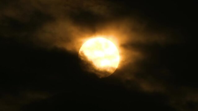 Big Full Moon with light rays getting covered by dark clouds
