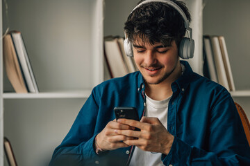 young male at home with headphones looking at mobile phone or smartphone