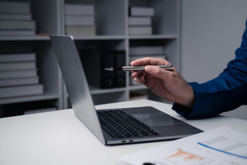 Close up view of businessman using laptop computer at office desk in the office room.