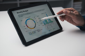 Close up view of young businessman using tablet to analyse the financial plan in the office room.