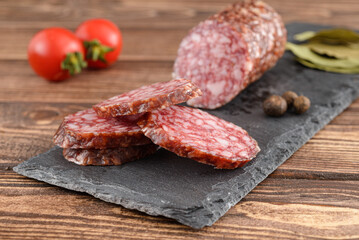 Salami sausage cut slices with tomato, bay leaf and garlic