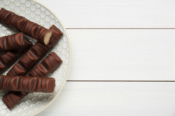 Tasty chocolate bars on white wooden table, top view. Space for text