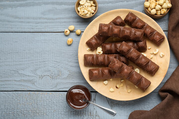 Sweet tasty chocolate bars with nuts on grey wooden table, flat lay. Space for text