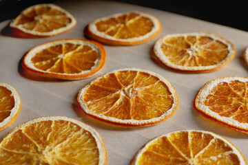 Many dry orange slices on parchment paper, closeup