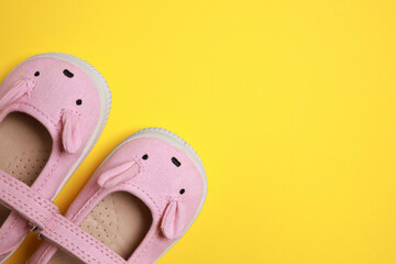 Cute baby shoes on yellow background, flat lay. Space for text