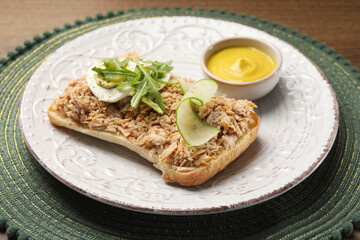 Delicious sandwich with tuna, boiled egg, vegetables and mustard sauce on green mat