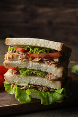 Delicious sandwich with tuna, tomatoes and lettuce on wooden table, closeup