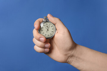 Man holding vintage timer on blue background, closeup