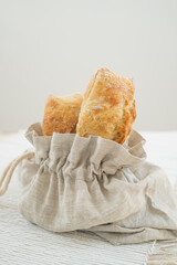Delicious ciabatta resting in an eco-friendly bread bag, presented on a rustic table with a cozy tablecloth.