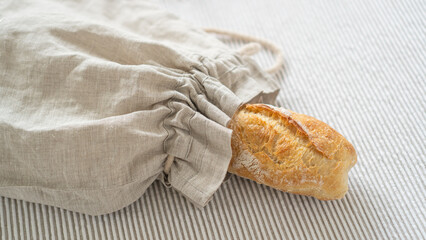 Artisanal ciabatta showcased in a sustainable linen bag, atop a wooden table adorned with a lovely tablecloth.
