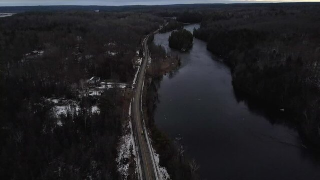 Cars Driving Along A Windy Road Along A River In Winter