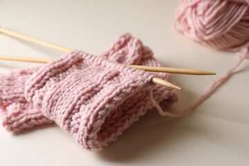Fototapeta na wymiar Pink knitting and needles on beige background, closeup