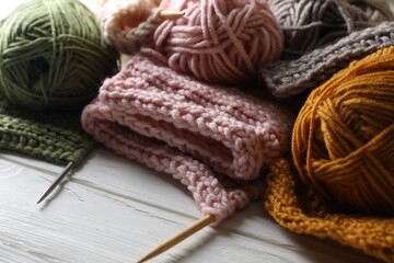 Fototapeta na wymiar Balls of soft yarns, knitting and needles on white wooden table
