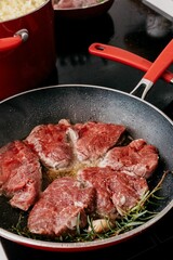 Close-up image of tender steak sizzling in a hot skillet on a kitchen stovetop