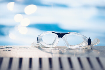Close-up shot of swimming goggles on swimming pool, text input background in swimming pool.