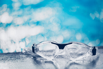 Close-up shot of swimming goggles on swimming pool, text input background in swimming pool.