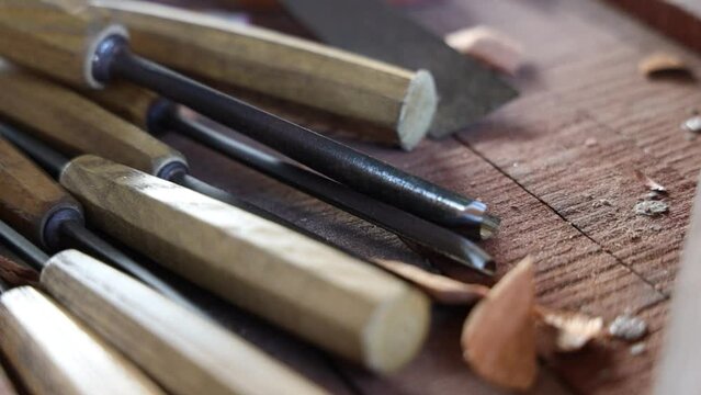 Closeup of an old craving knifes tools on a wooden surface at a workshop