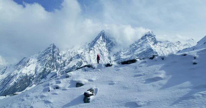 Stunning drone footage of a boy in a red jacket admiring Himalayan landscapes at Manaslu Circuit Trek, Nepal. Parallax shot showcases panoramic views of snow-capped peaks, perfect for adventure travel