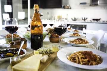 Table set for lunch in the beautiful kitchen with genuine products of Italian cuisine - tasty spaghetti with tomato sauce, amazing aged cheese with jams and honey, grilled vegetables and meatballs