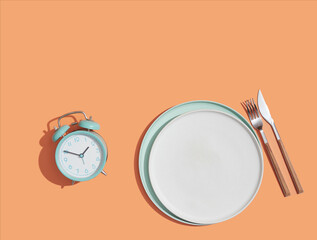 Mealtime, healthy eating concept, dieting, weight loss and intermittent fasting. Alarm clock next...