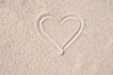 Sand background. Simple image of heart drawn on sand. Sandy beach. Blank negative space for copy.