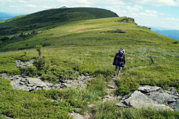Obraz premium Young hiker climbing a rocky mountain trail, enjoying the warm sunshine