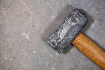 Closeup shot of a sledgehammer with shallow depth of field on a concrete floor