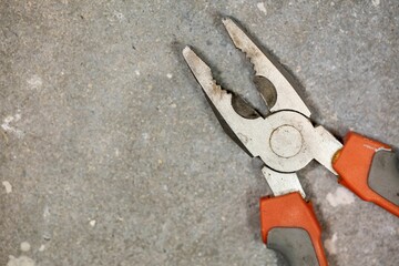Closeup shot of combination pliers with shallow depth of field on a concrete floor