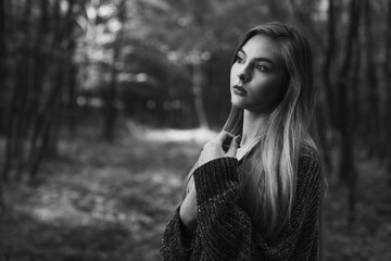 Caucasian woman with blonde hairs posing in forest and looking side