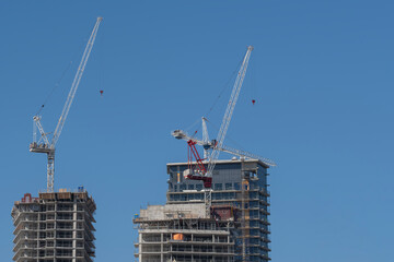 Construction cranes next to modern high rise tall condo and office building that are being built....
