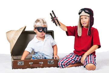 Two boys in the form playing with a toy plane dressed as old school pilots