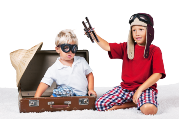 Two boys in the form playing with a toy plane dressed as old school pilots