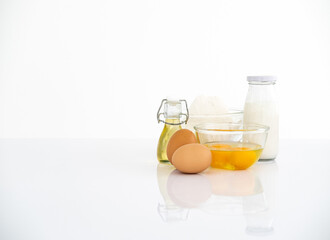Baking ingredients on white reflect table over defocused white kitchen wall background.