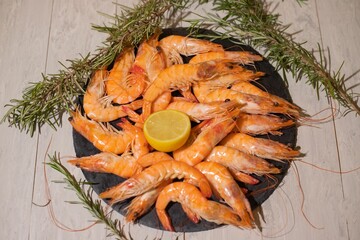 Closeup of red shrimps with a lemon on a plate on a wooden table