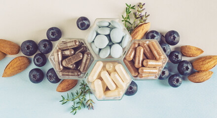 Various capsules with dietary supplements or vitamines and fresh blueberry and nuts