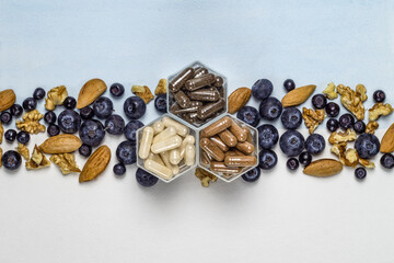 Various capsules with dietary supplements or vitamines and fresh blueberry and nuts